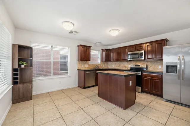 a kitchen with stainless steel appliances granite countertop a stove top oven a sink dishwasher a refrigerator and a microwave