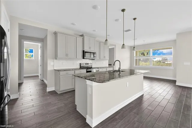 a large kitchen with stainless steel appliances kitchen island granite countertop a sink a stove and a wooden floors