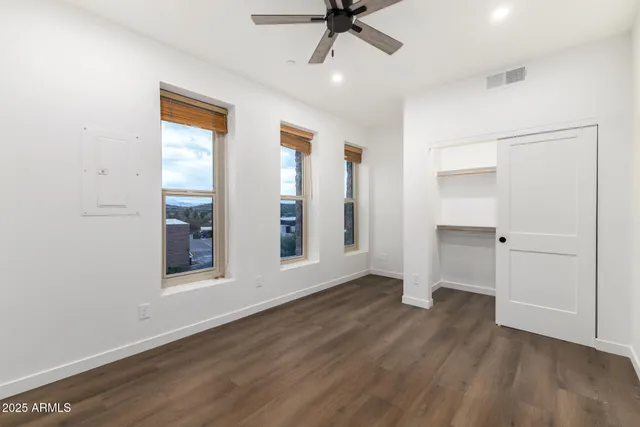 an empty room with wooden floor cabinet and windows