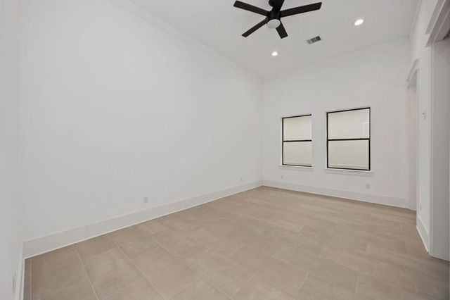 an empty room with chandelier fan and windows