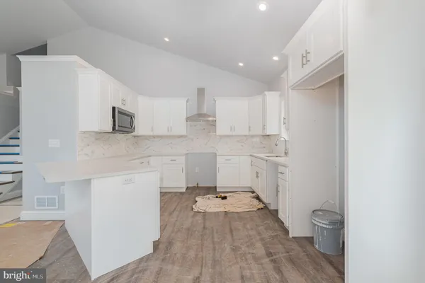a large kitchen with kitchen island a stove a sink dishwasher and a dining table with wooden floor