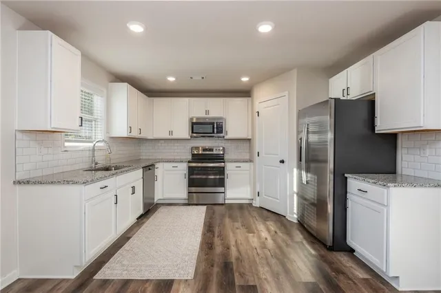 a kitchen with granite countertop a refrigerator stove and sink