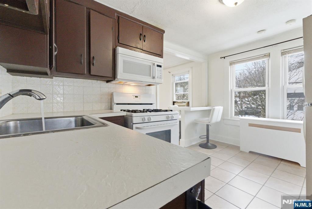 64 John Ryle Avenue Haledon, NJ 07508 - Photo 17 of 44 a kitchen with a stove a sink and a microwave