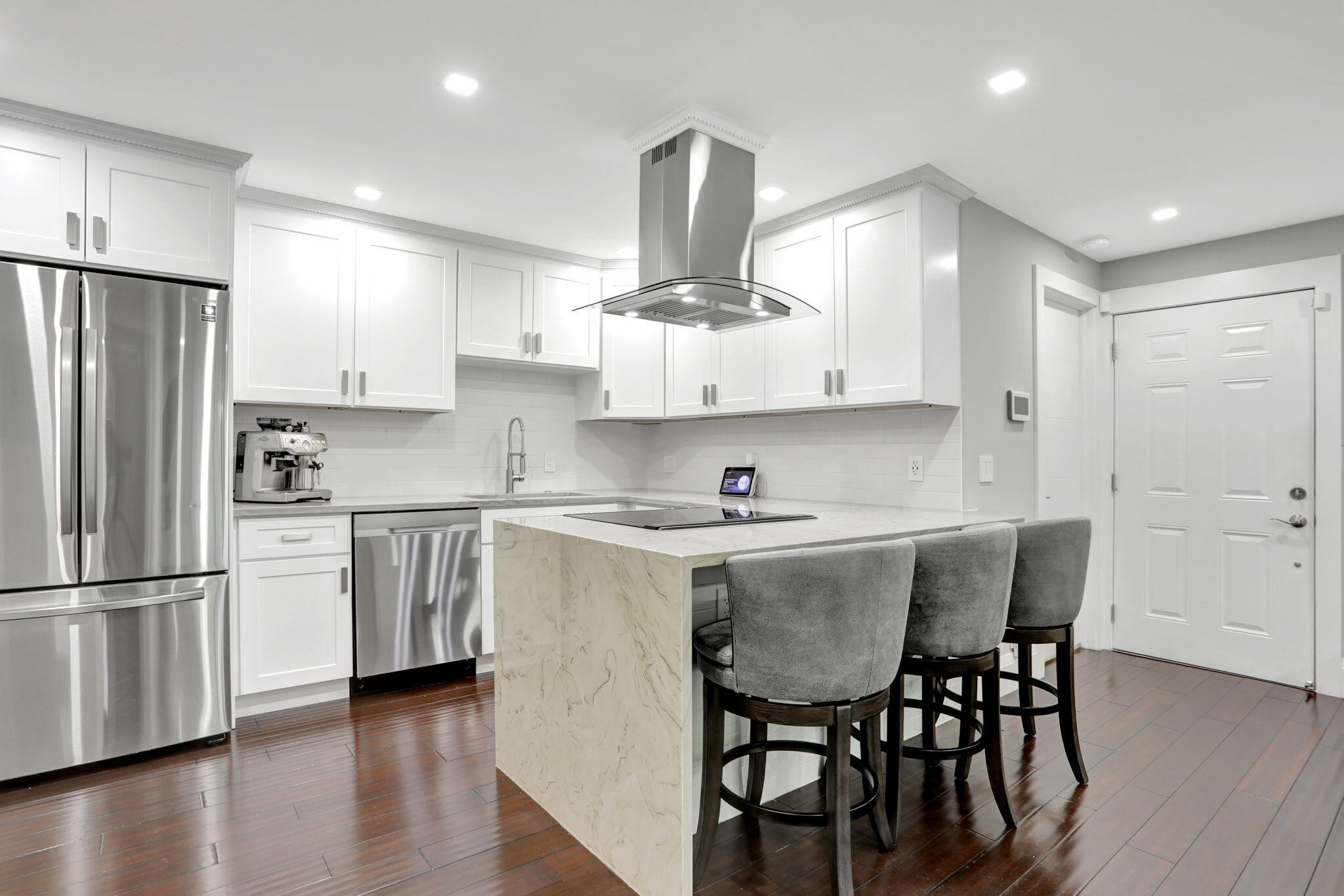 a kitchen with stainless steel appliances a dining table chairs refrigerator and sink