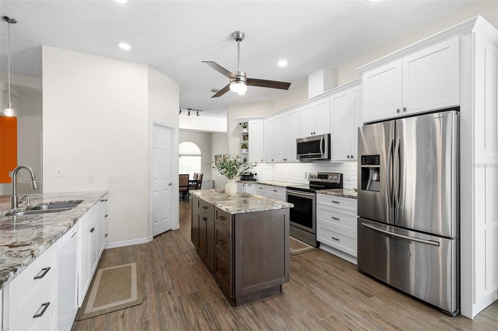 2513 Regal River Road Valrico, FL 33596 - Photo 11 of 46 a kitchen with stainless steel appliances kitchen island granite countertop a refrigerator a stove oven a sink dishwasher and white cabinets with wooden floor
