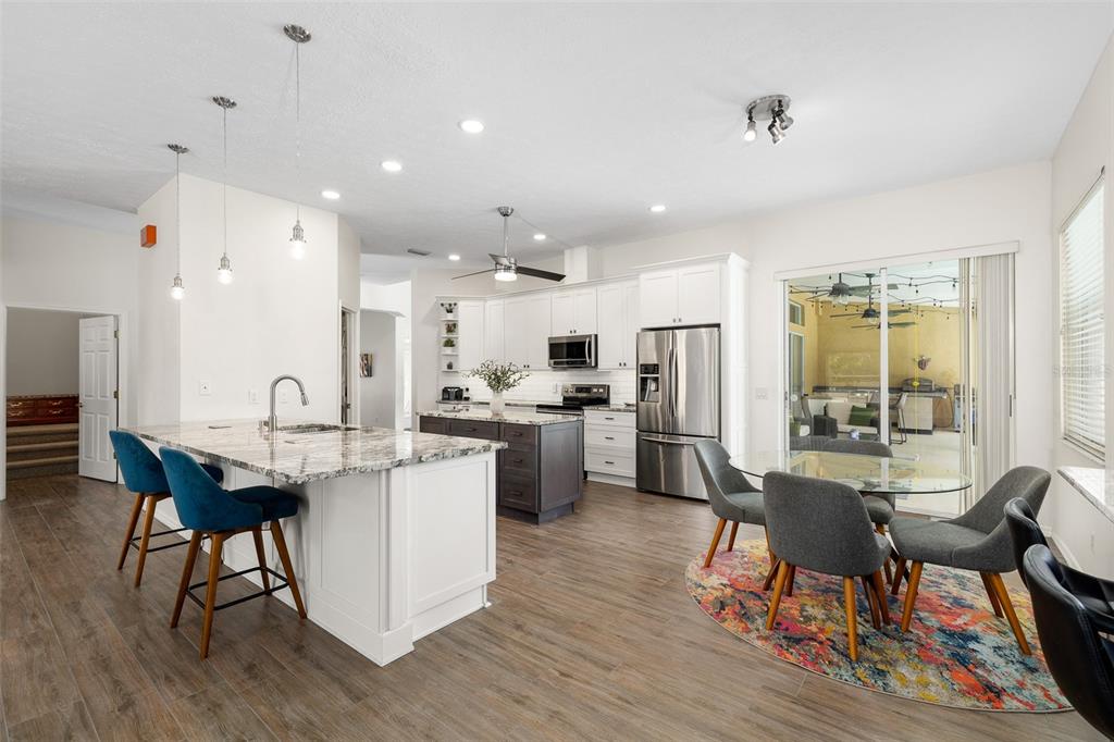 2513 Regal River Road Valrico, FL 33596 - Photo 12 of 46 a open dining room with stainless steel appliances kitchen island granite countertop a dining table and chairs