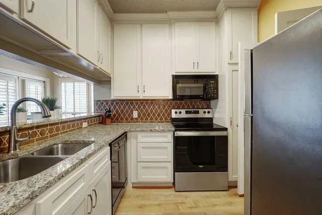 a kitchen with granite countertop a stove sink and cabinets