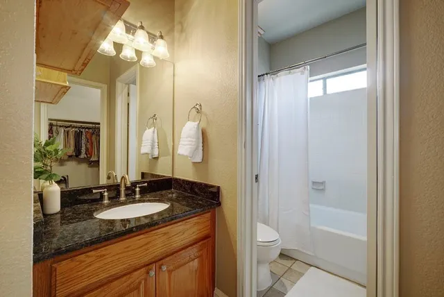 a bathroom with a granite countertop sink toilet and shower