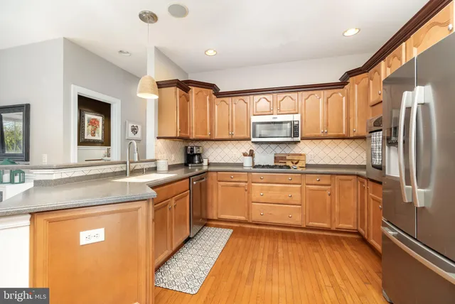 a kitchen with stainless steel appliances granite countertop a sink refrigerator and cabinets