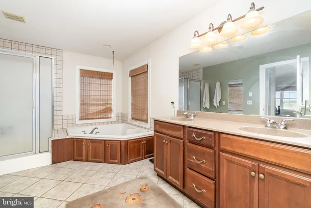 a spacious bathroom with a tub sink and mirror