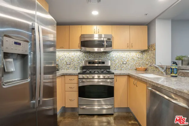 a kitchen with stainless steel appliances granite countertop a stove a refrigerator and a sink