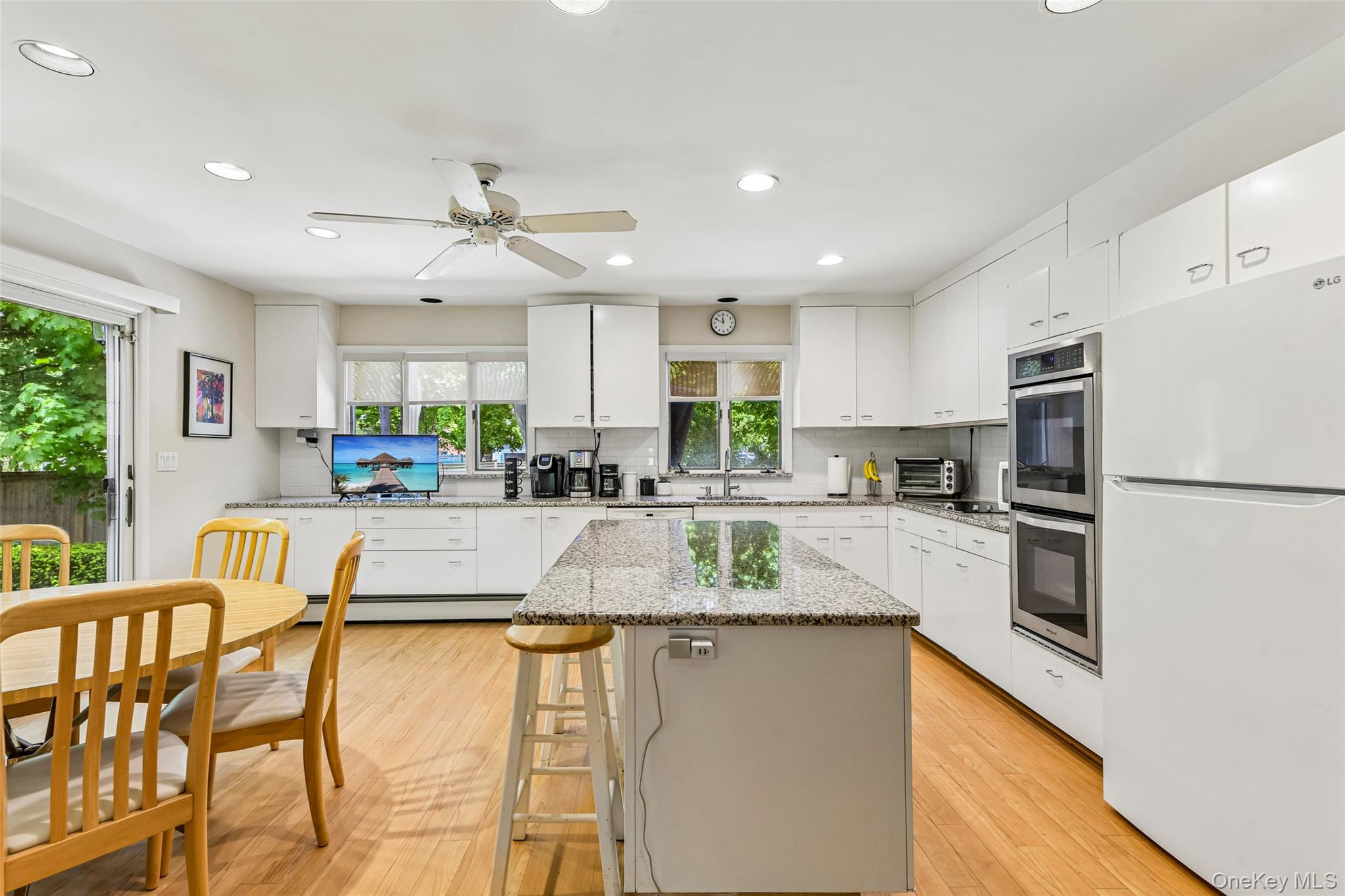 100 Hewlett Neck Road Woodmere, NY 11598 - Photo 14 of 45 a kitchen with stainless steel appliances granite countertop a refrigerator a stove top oven a sink dishwasher and white cabinets with wooden floor