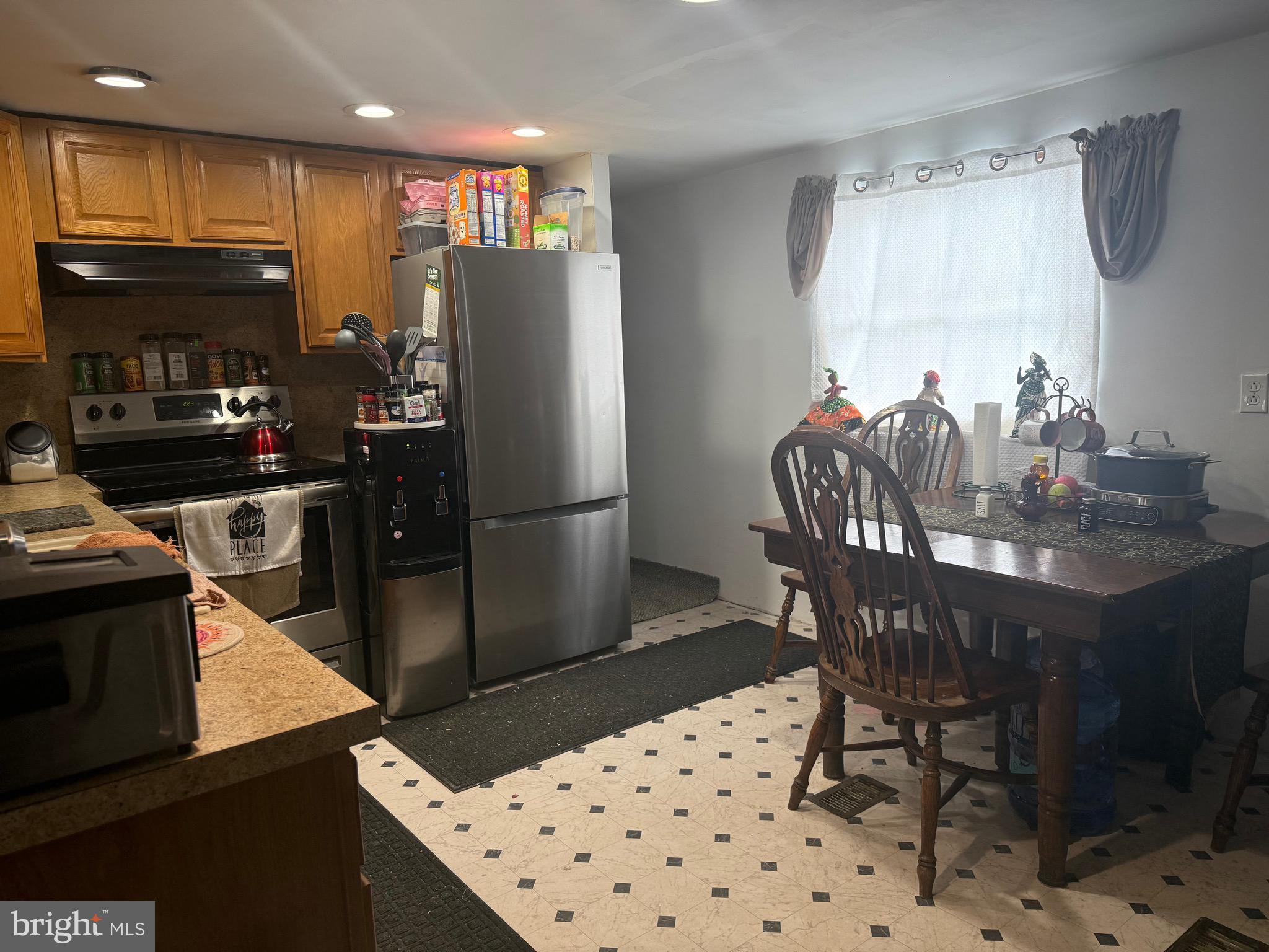 1910 Schubert Road, Unit 4 Bethel, PA 19507 - Photo 8 of 17 a kitchen with granite countertop a refrigerator a stove a microwave a dining table and chairs with wooden floor