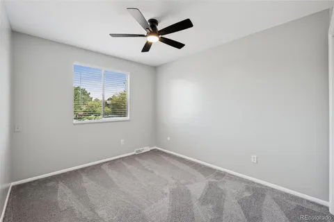 an empty room with a window and a fan