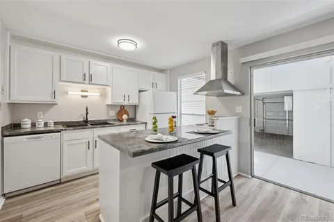 a kitchen with stainless steel appliances granite countertop a sink a stove and chairs