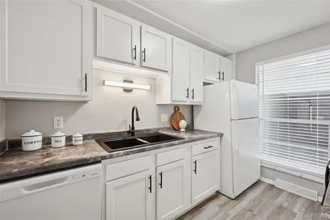 a kitchen with granite countertop white cabinets white appliances and sink