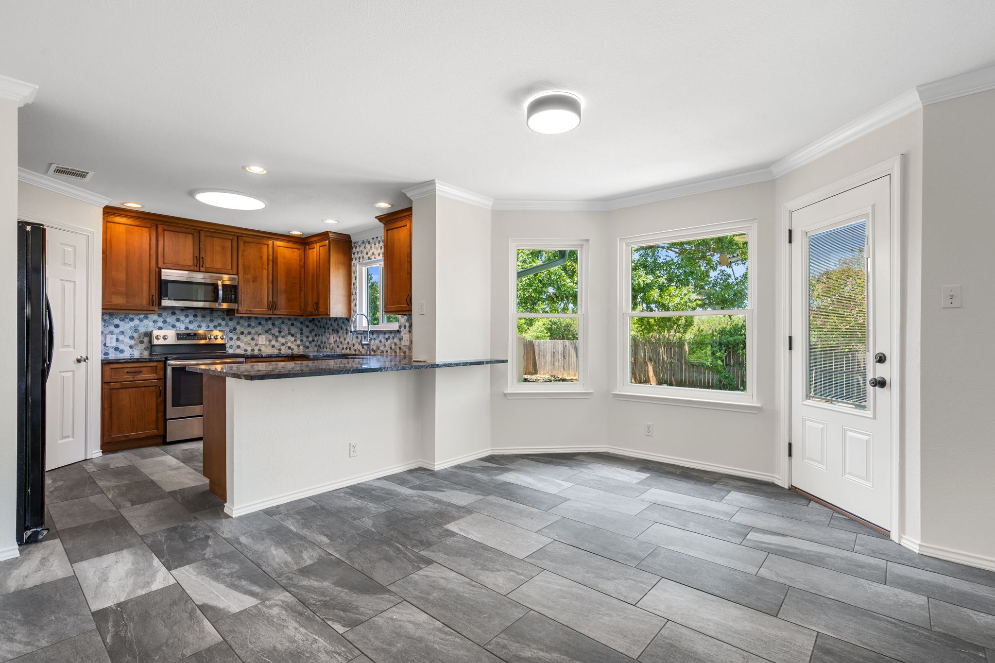 2440 Madeline Loop Cedar Park, TX 78613 - Photo 12 of 33 Kitchen with stainless steel appliances, decorative backsplash, wood finish cabinets, ornamental molding, and dark stone countertops