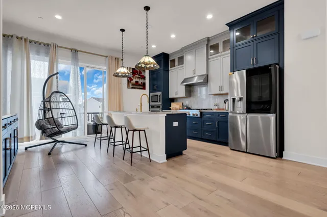 a kitchen with stainless steel appliances granite countertop a refrigerator a stove top oven a sink dishwasher and white cabinets with wooden floor
