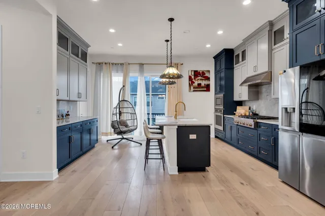 a large kitchen with stainless steel appliances granite countertop a large stove a sink dishwasher and a refrigerator with wooden floor