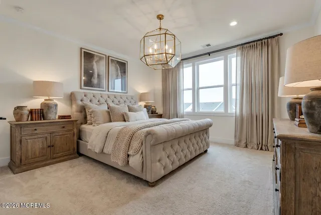 a spacious bedroom with a bed a chandelier and mirror