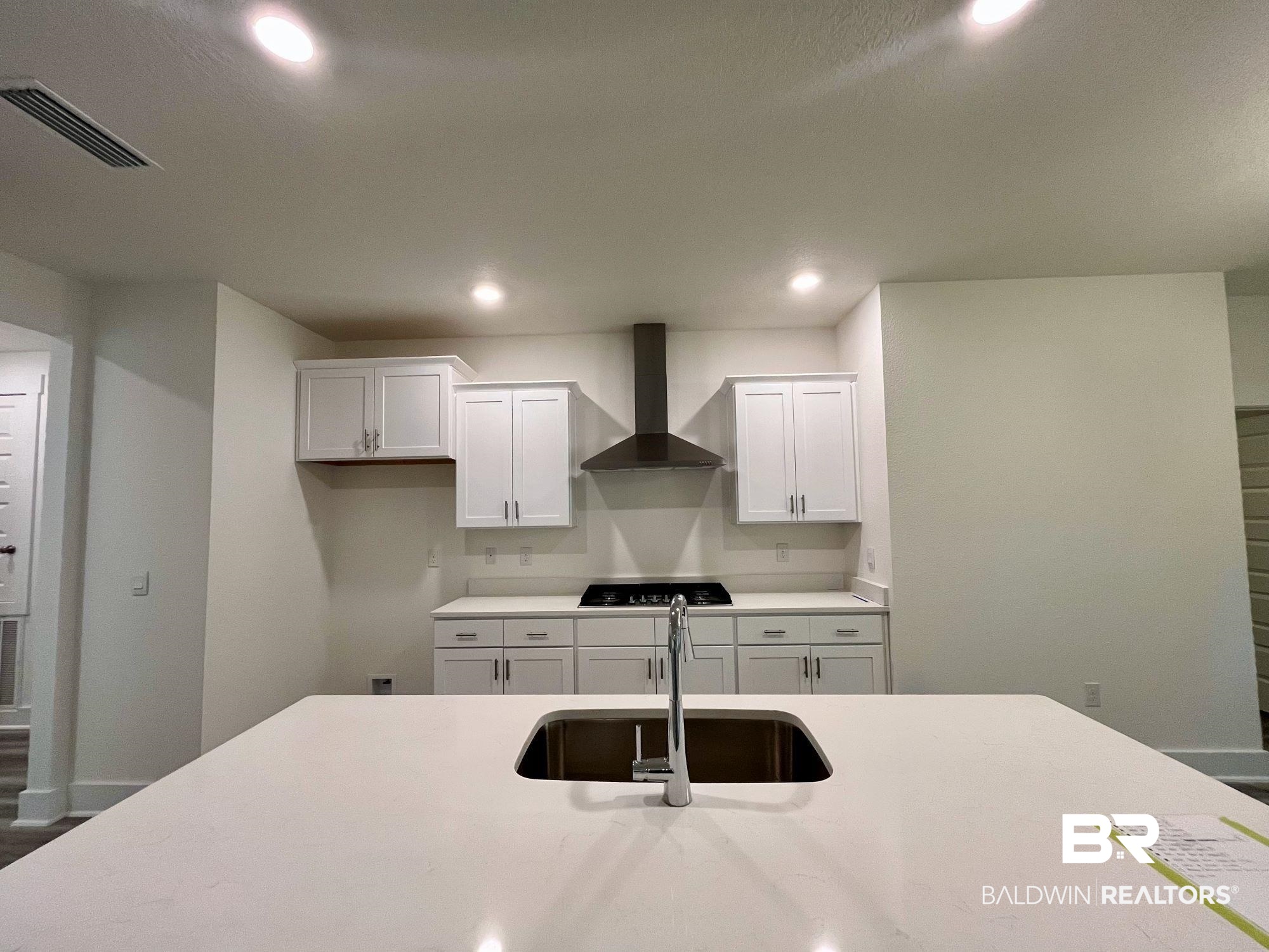 334 Barndling Street Fairhope, AL 36532 - Photo 14 of 34 Kitchen with white cabinets, wall chimney exhaust hood, sink, and black gas cooktop