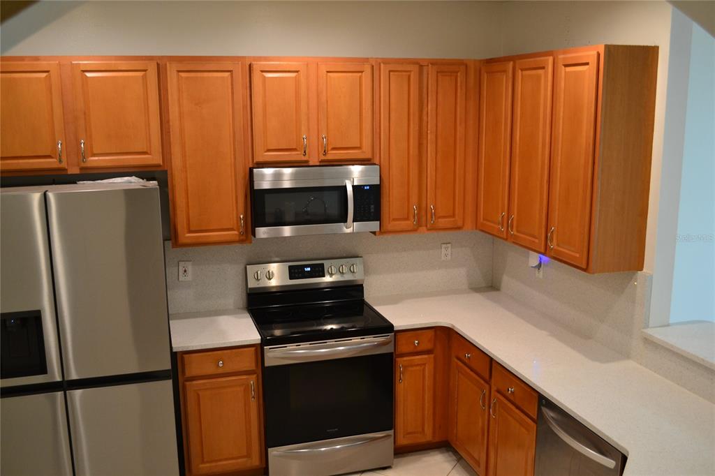 11235 Kapok Grand Circle Madeira Beach, FL 33708 - Photo 5 of 34 a kitchen with stainless steel appliances a refrigerator a stove a sink and a microwave