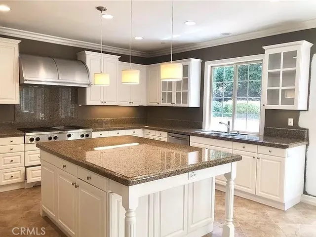 a kitchen with granite countertop a sink and white cabinets