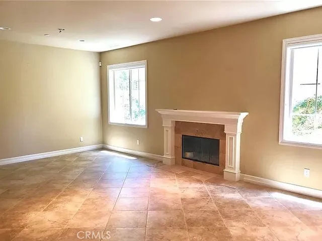 a view of an empty room with a window and fireplace
