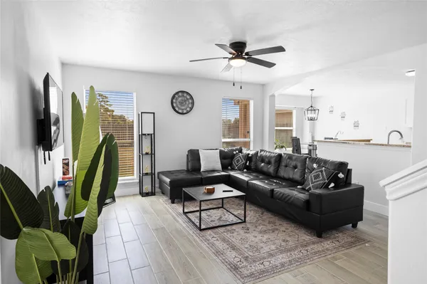 a living room with furniture a clock on a bookshelf and a flat screen tv