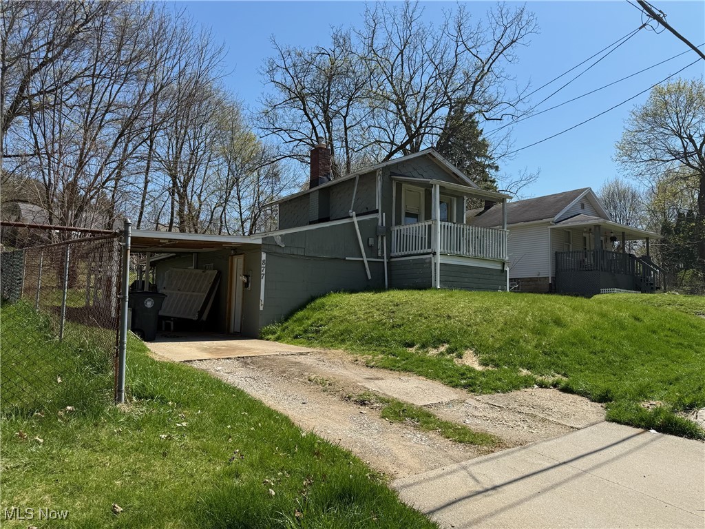 877 Garfield Street Akron, OH 44310 - Photo 16 of 16 View of front of house featuring a carport, dirt driveway, a front lawn, and a chimney
