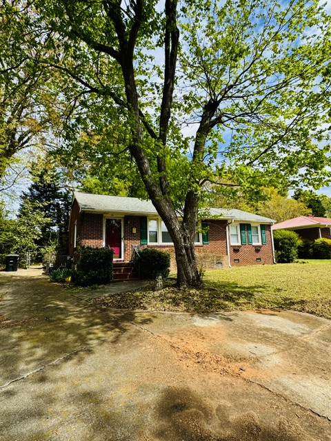 This charming brick residence offers a verdant front yard and a classic porch, perfect for peaceful living.