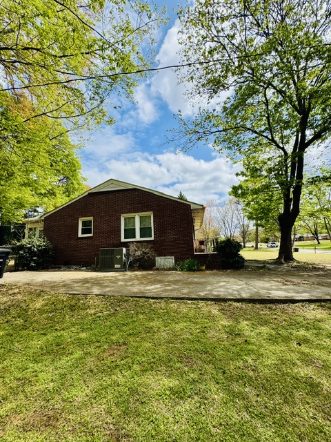 212 Beauregard Avenue Anderson, SC 29621 - Photo 4 of 5 This classic brick residence boasts a neatly kept yard and mature trees under a bright sky.