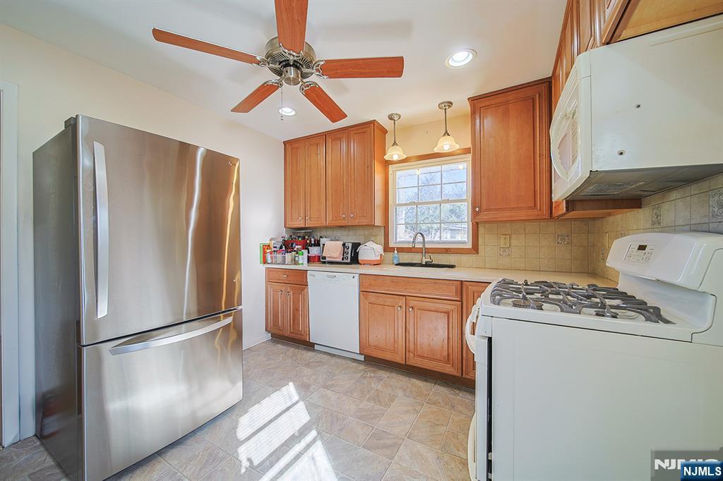 50 Knolls Road Bloomingdale, NJ 07403 - Photo 16 of 36 a kitchen with stainless steel appliances granite countertop a refrigerator a sink dishwasher a stove with white cabinets and wooden floor