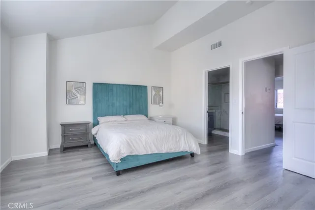 a spacious bedroom with a bed and wooden floor