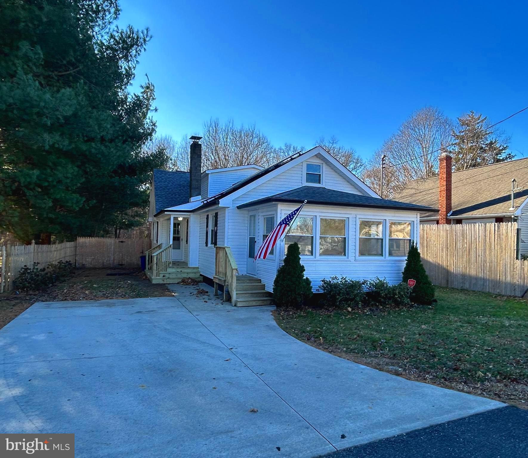 a view of a yard in front of a house with plants and large tree