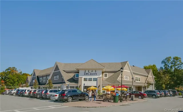 a front view of a building with lot of cars and trees
