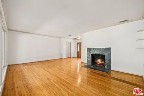a view of empty room with wooden floor and fireplace