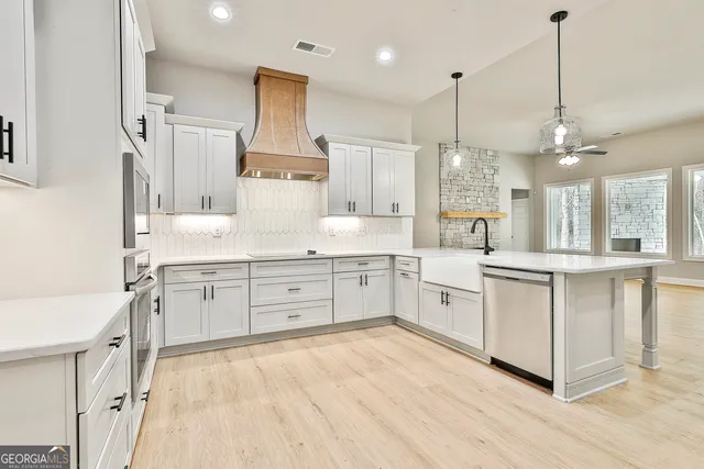 a large white kitchen with a refrigerator a sink dishwasher a oven and a dining table with wooden floor