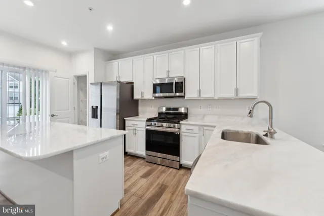 a kitchen with stainless steel appliances a stove a sink a refrigerator a microwave and cabinets