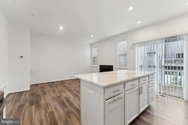 a kitchen with a sink dishwasher a stove and white cabinets with wooden floor