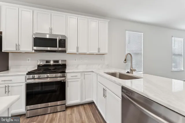 a kitchen with stainless steel appliances granite countertop white cabinets a sink and a stove