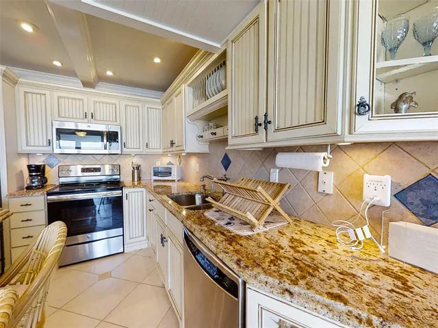 a kitchen with kitchen island granite countertop a sink cabinets and stainless steel appliances