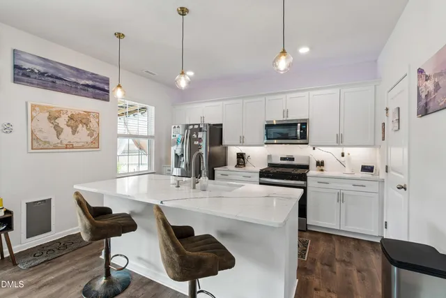 a kitchen with stainless steel appliances granite countertop a stove a refrigerator a kitchen island a dining table and chairs