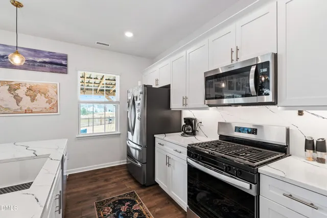 a kitchen with stainless steel appliances a stove a microwave a sink and cabinets