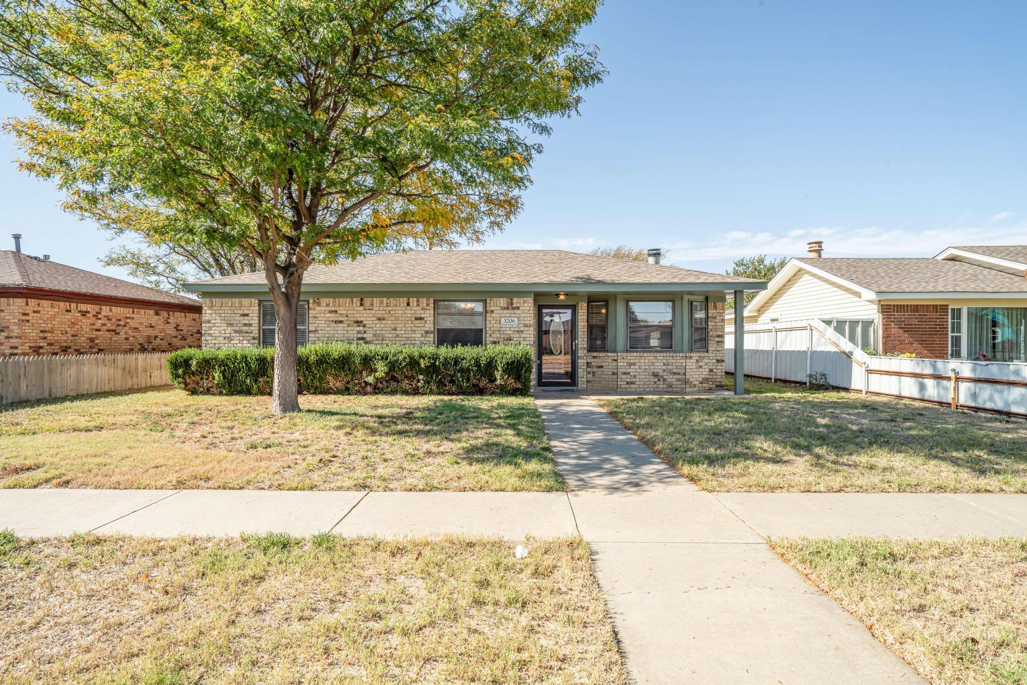 a view of a white house next to a yard with a tree