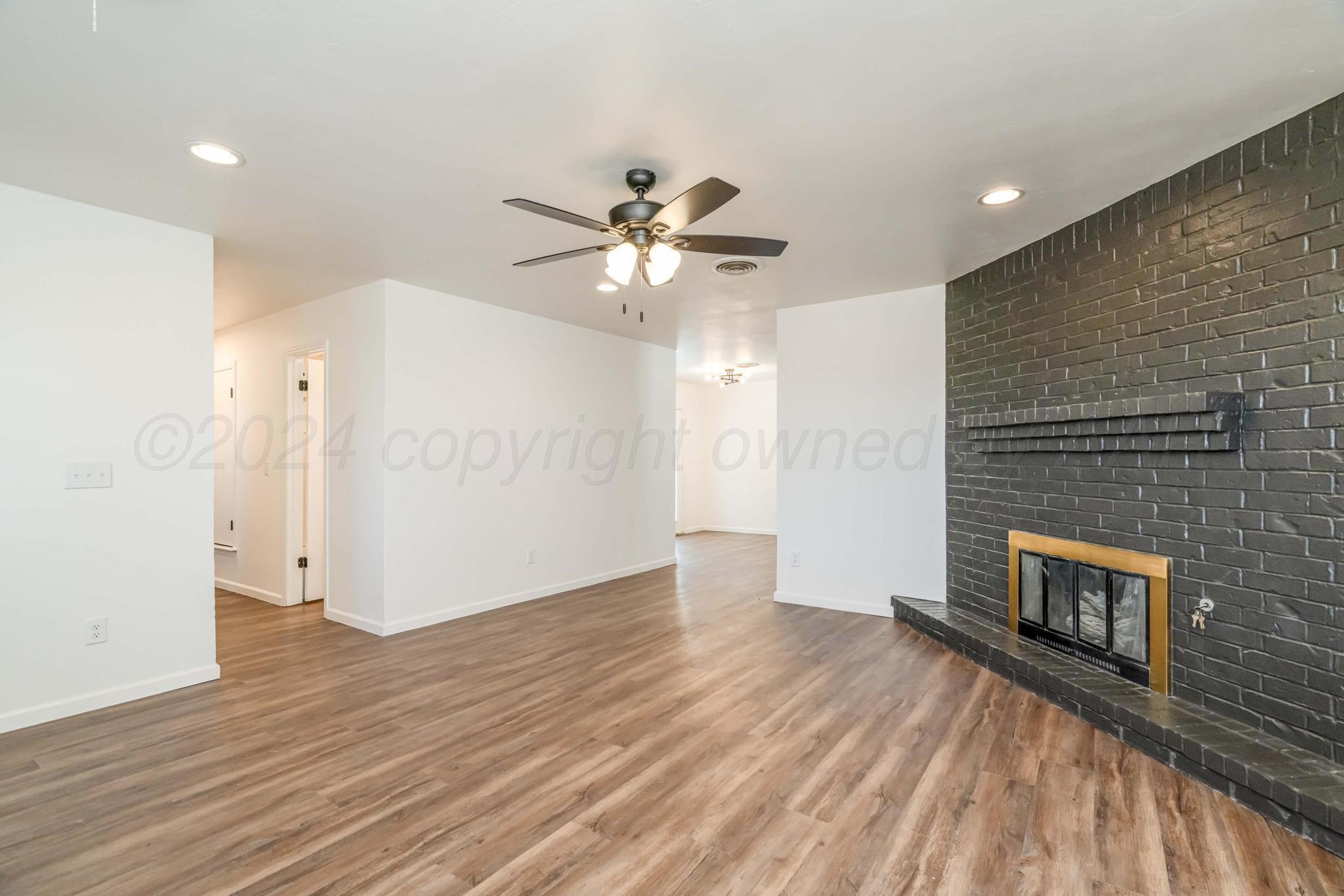 3206 Wind Song Drive Amarillo, TX 79103 - Photo 4 of 27 wooden floor in an empty room with a fireplace