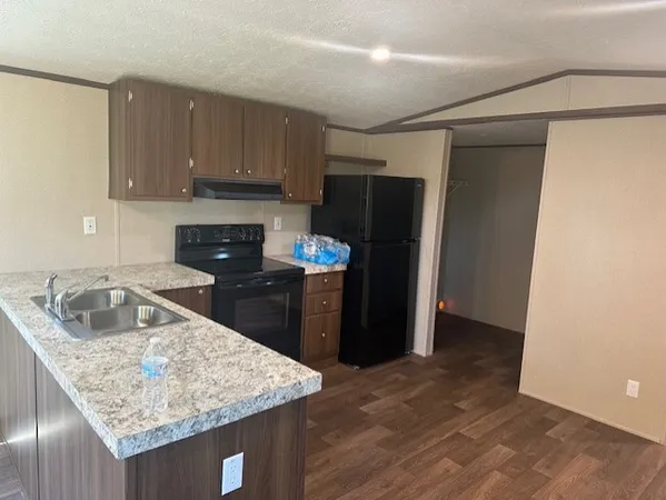 a kitchen with stainless steel appliances granite countertop a refrigerator a sink dishwasher with wooden cabinets and floor