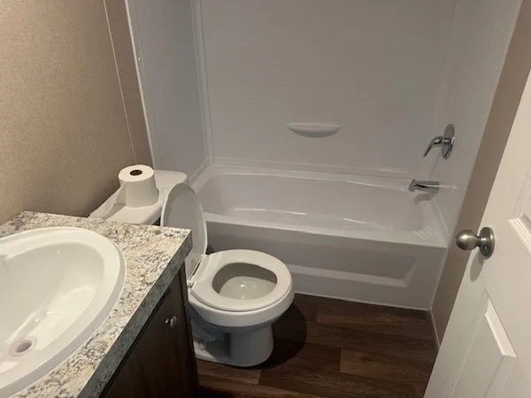a bathroom with a granite countertop toilet sink and mirror