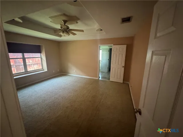 an empty room with windows and ceiling fan