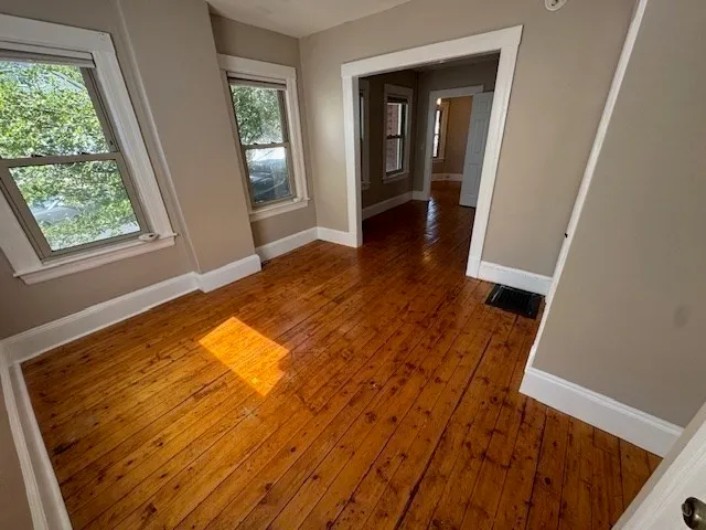 a view of an empty room with wooden floor and a window